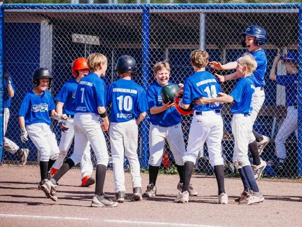 Jongens in honkbaluniform vieren succes op het veld, jonge sporters die plezier hebben bij Little League jeugdbaseball.